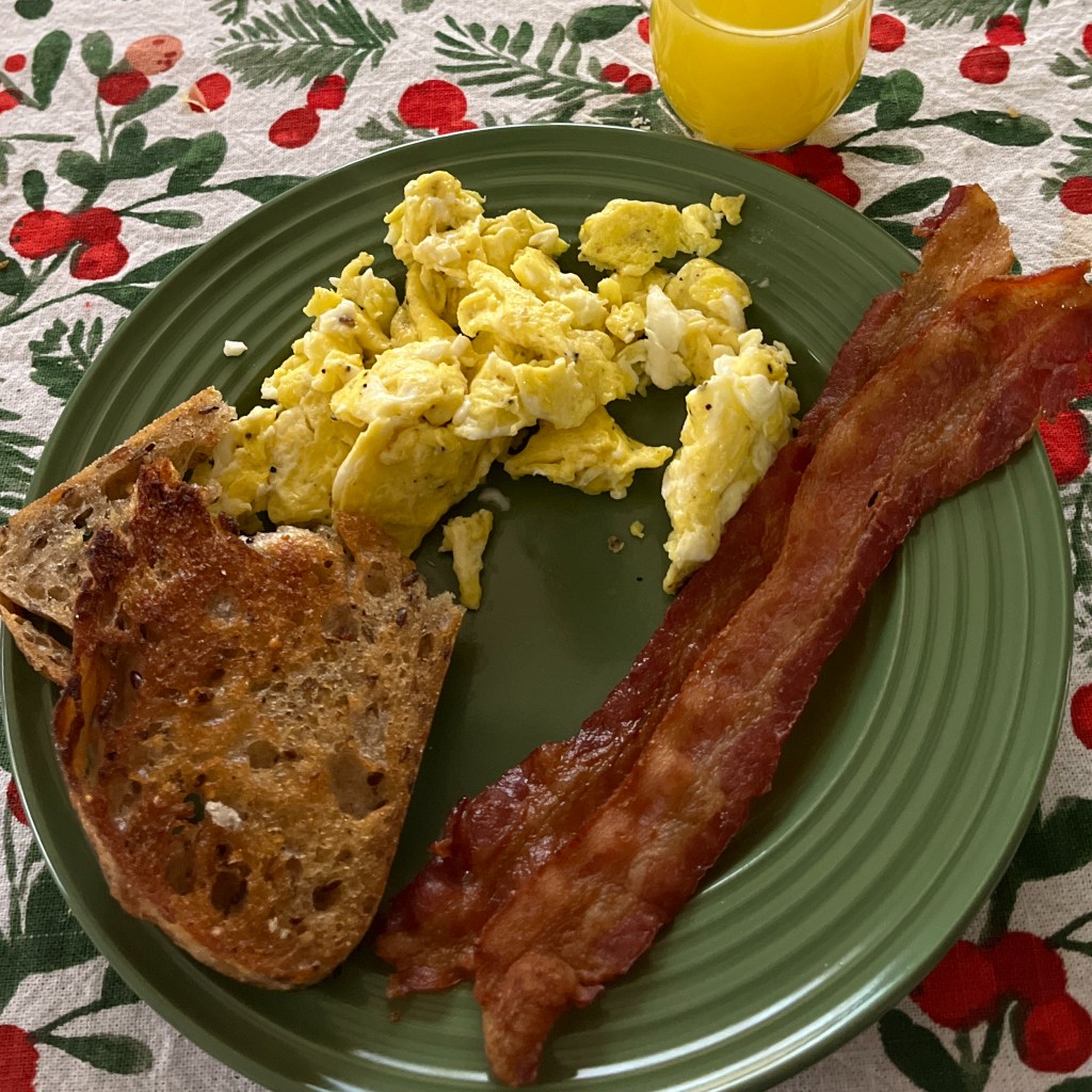 scrambled eggs, bacon, and toast on a green plate